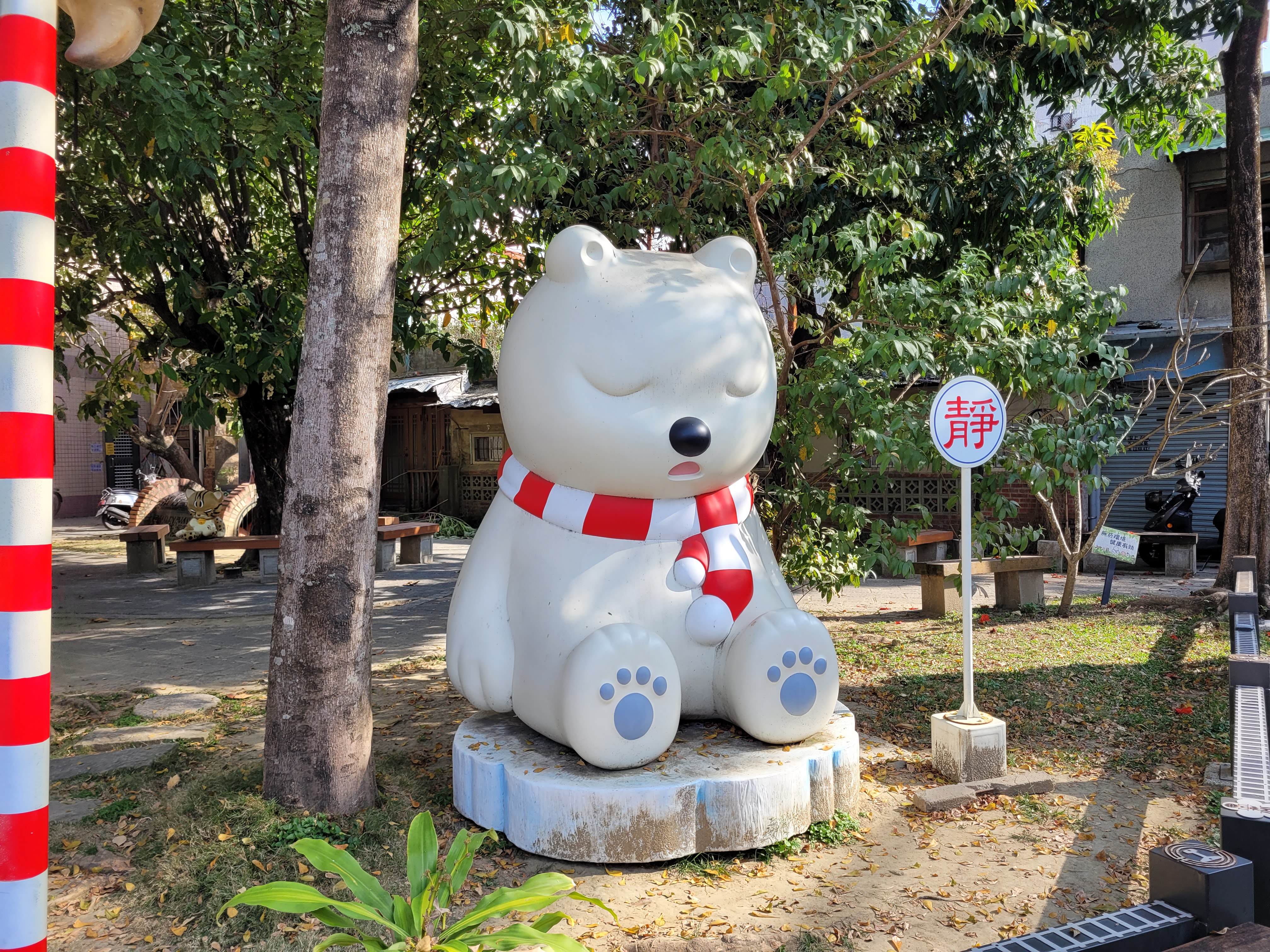 07/03/2025 - Sleeping bear -
					This statue is located in the Sleeping Forest, a small park in Chiayi near the Hinoki village.
					An illustrator designed a group of cute sleeping animals with the theme of 'Sleeping', including a white bear, a pink elephant, a stone tiger (that we can see behind), a penguin, and a fox.
					They are waiting, sleeping peacefully under the trees of the park, allowing travelers in a hurry to take a rest with the sleeping animals.