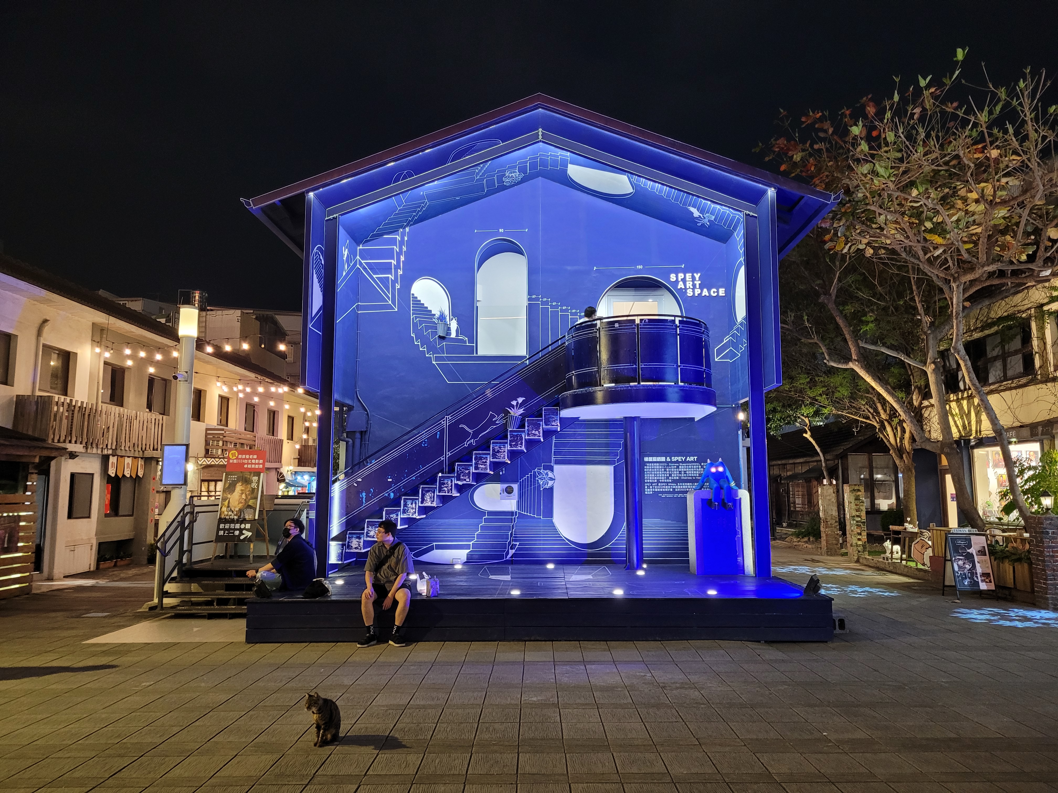 22/03/2025 - Blueprint Cat House - 
					This picture was taken in the Blueprint Culture & Creative Park	in Tainan.
					It is a place with a lot of art installations and shops.
					There was this house decorated with blue and white art and cats, one even went through the wall!