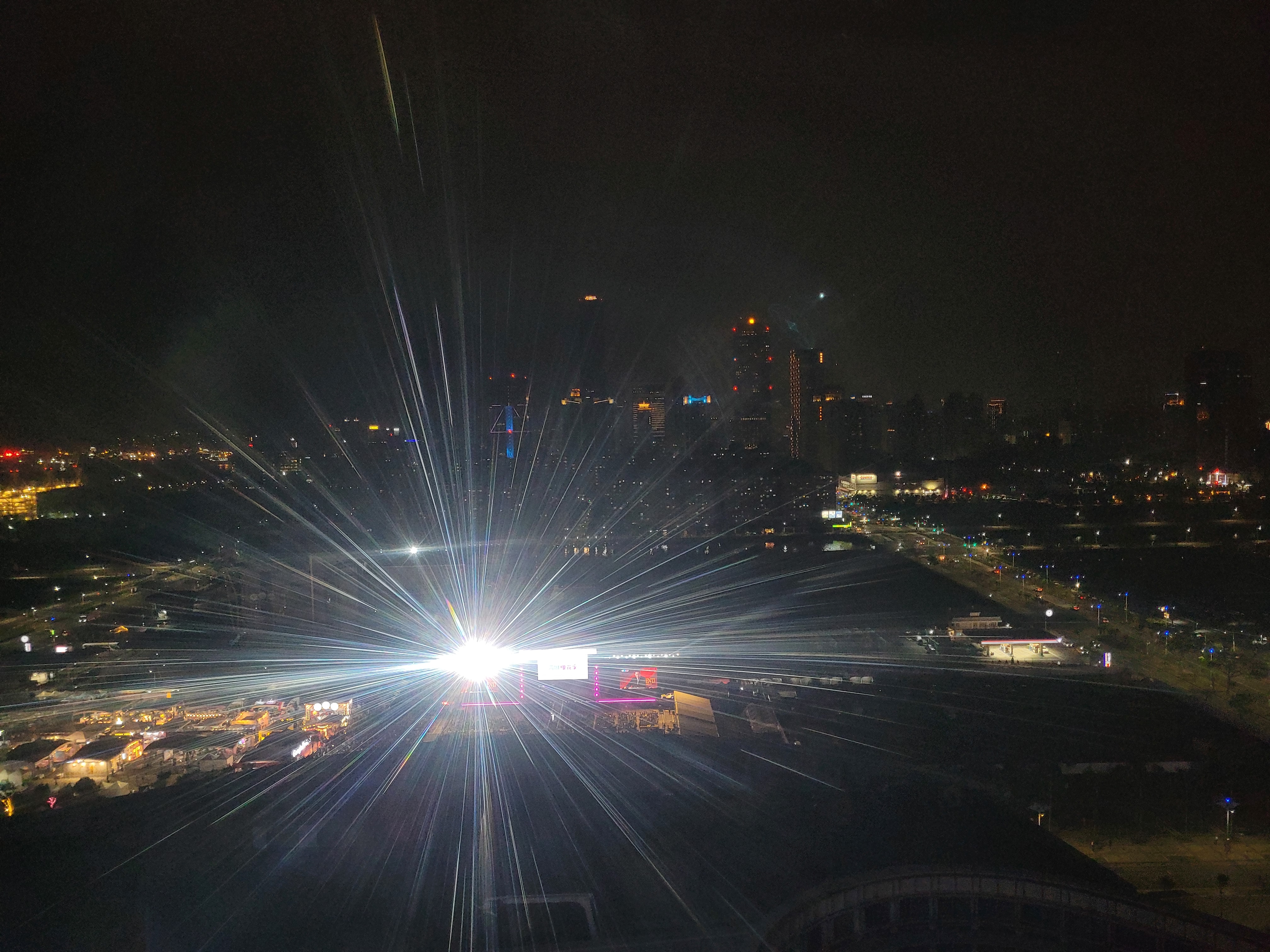 20/04/2025 - Kaohsiung view during a flash - 
						View of Kaohsiung from the Kaohsiung Eye Ferris wheel while a concert was happening below.
						At the moment the photo was taken, a stage projector emitted a bright flash of light that illuminated the camera.